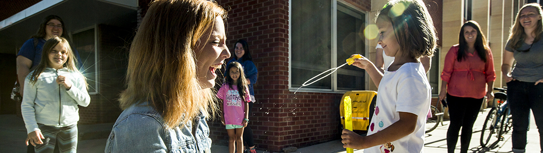 A group of children play outside with their teacher.