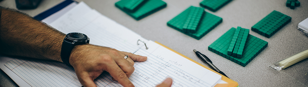 A group of teachers, only their hands showing, pick through green Unit Ten blocks on a table.