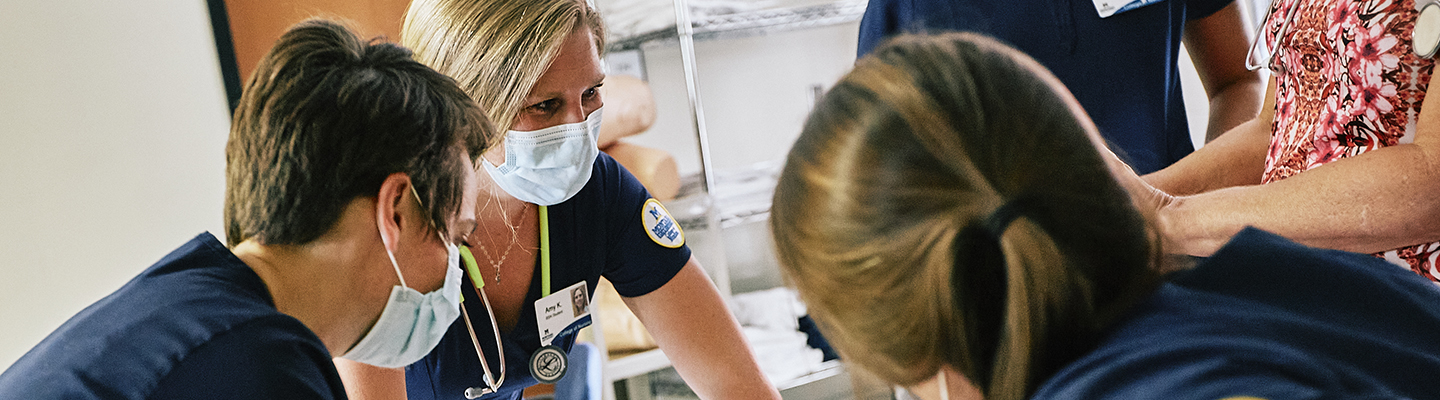 A group of women wearing PPE lead a nursing simulation.