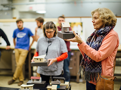 A professor critiques a student's model in an architecture studio.