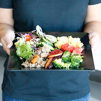 person holding a plate of food in dining hall