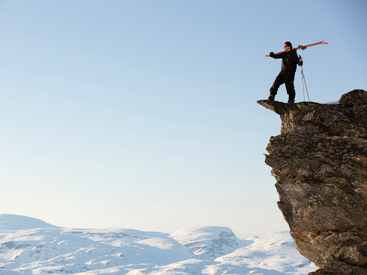 A person holding skis standing on a cliffside