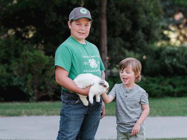 4-H member holding a rabbit while a younger boy pets it, image taken by Tom-Aldrich