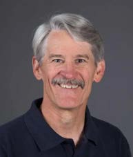 a headshot of a man with grey hair and mustache. 