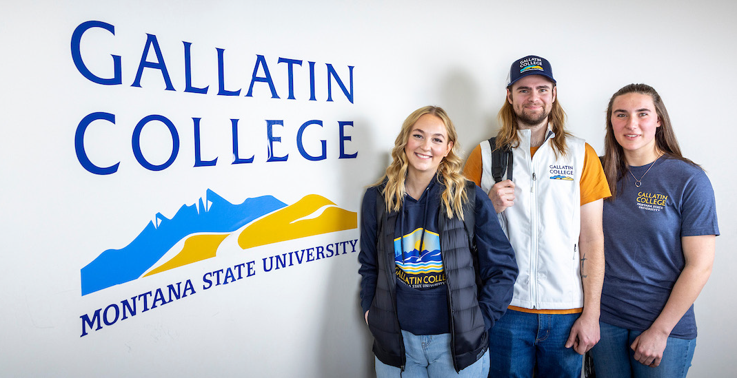 students posing against the branded wall that reads "Gallatin College"