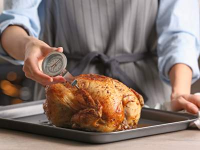 cook with thermometer in chicken