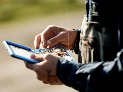 An angler picking out a fly from a tackle box.