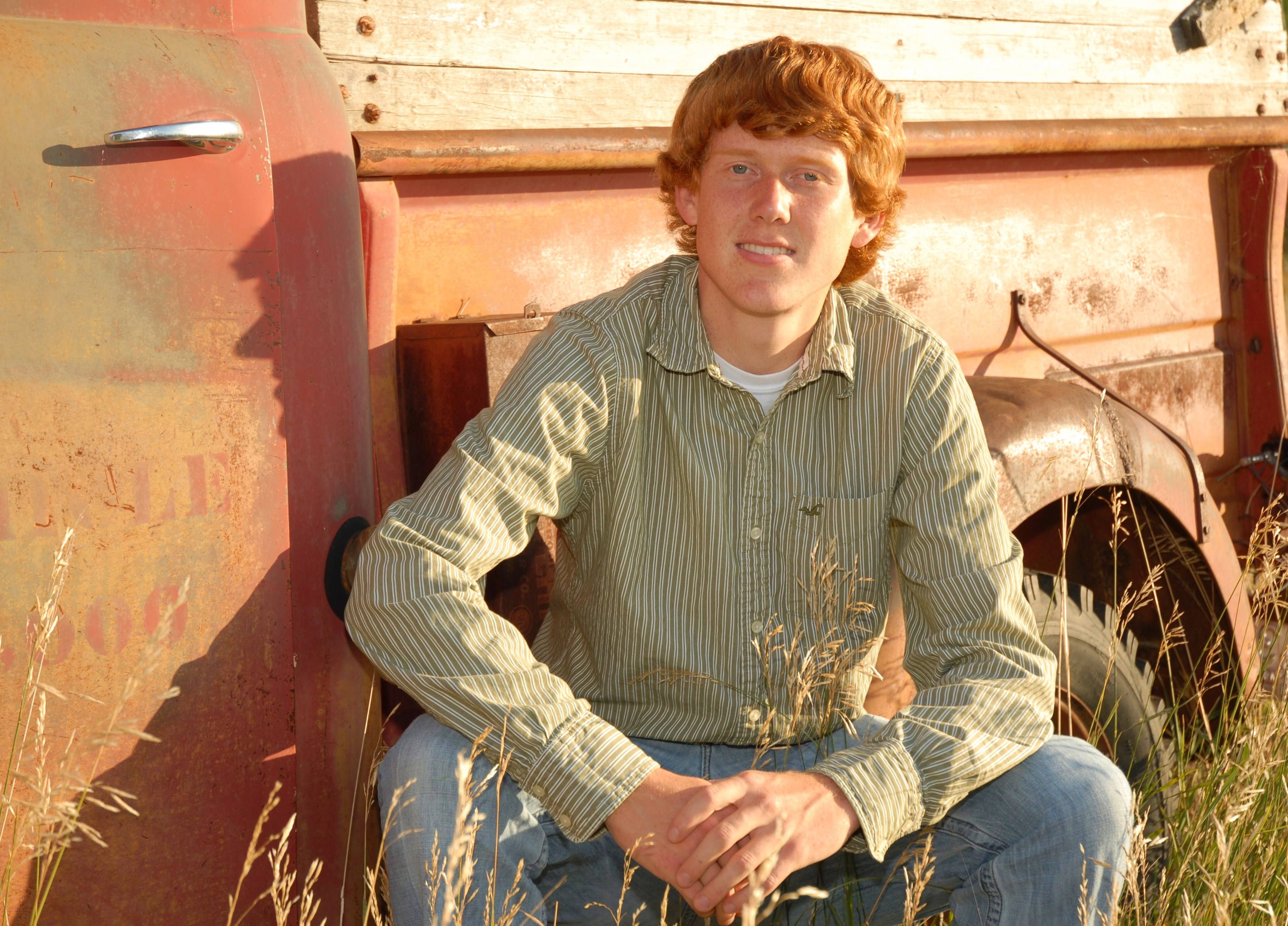 Male student sitting in front of a piece of farm equipment