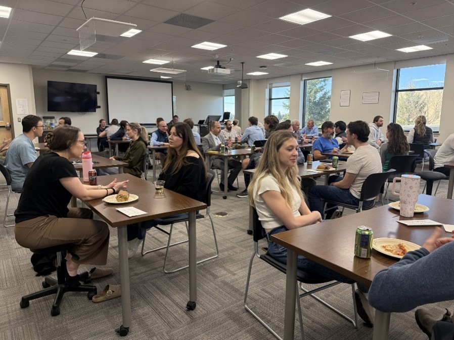 Medical students and others sitting at long tables talking to each other. 
